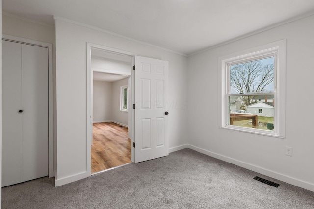 unfurnished bedroom with carpet floors, ornamental molding, and a closet