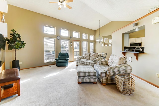 living room featuring ceiling fan with notable chandelier, light colored carpet, and high vaulted ceiling