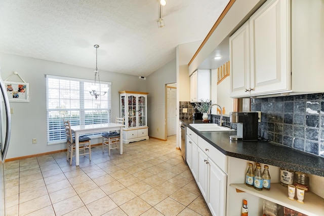 kitchen with sink, tasteful backsplash, white cabinets, decorative light fixtures, and stainless steel dishwasher