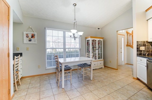 tiled dining area with lofted ceiling, a textured ceiling, and a chandelier