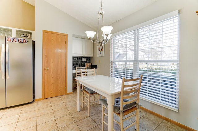 dining area with a notable chandelier, lofted ceiling, and light tile patterned floors