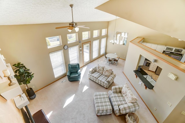 carpeted living room with ceiling fan with notable chandelier, high vaulted ceiling, and a textured ceiling