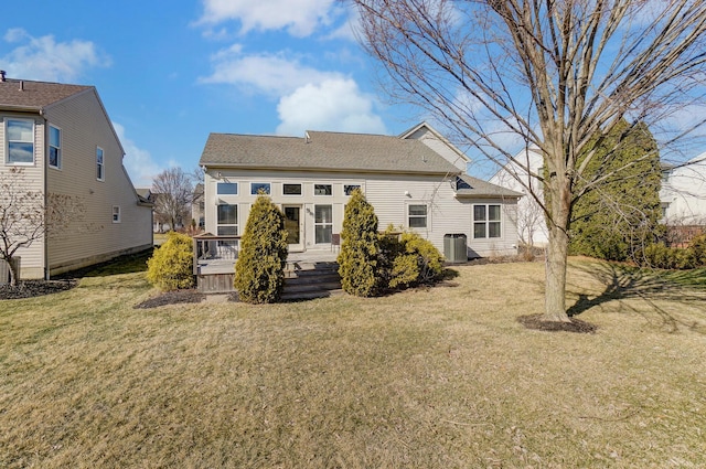 rear view of house with central AC unit and a yard