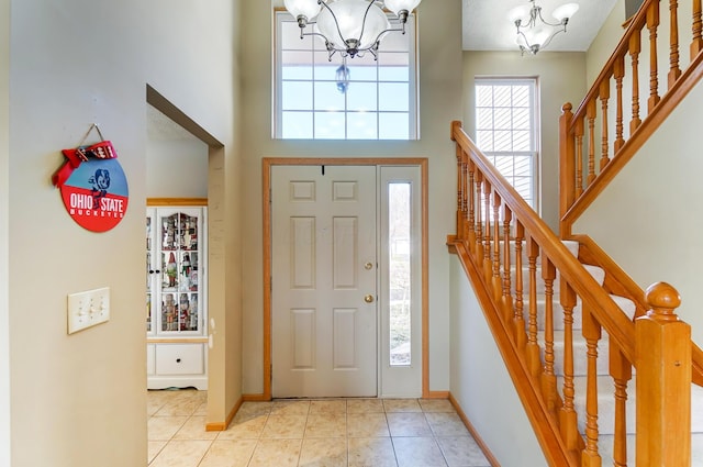 entrance foyer featuring light tile patterned floors, a towering ceiling, and a chandelier