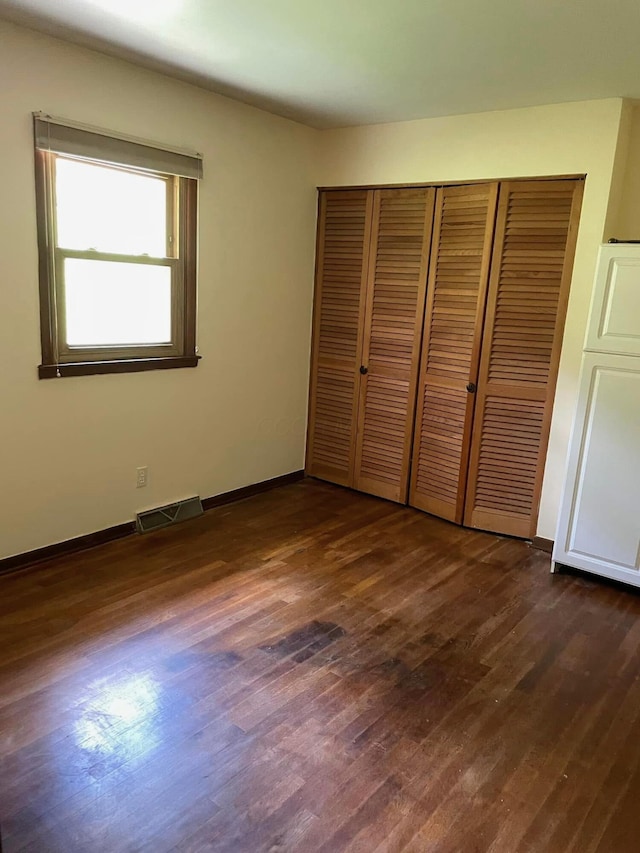 unfurnished bedroom featuring dark hardwood / wood-style flooring and a closet