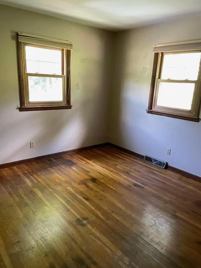 empty room featuring a healthy amount of sunlight and dark hardwood / wood-style flooring