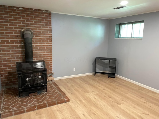 living room with ornamental molding, a wood stove, and light hardwood / wood-style floors