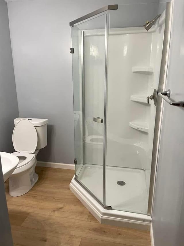 bathroom featuring hardwood / wood-style flooring, toilet, and a shower with door