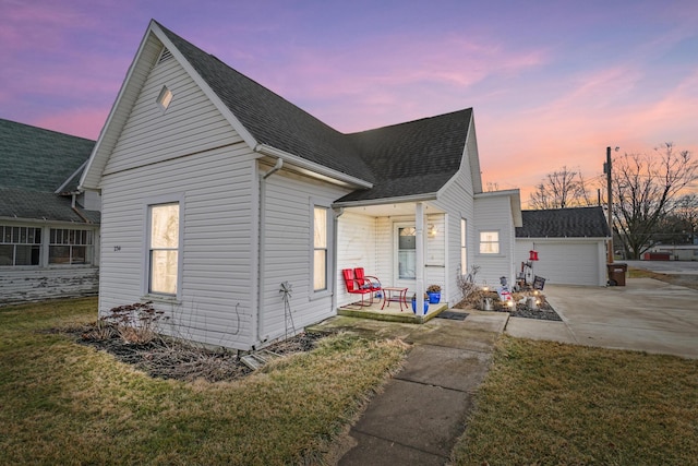 view of front of property featuring a porch, a garage, and a yard