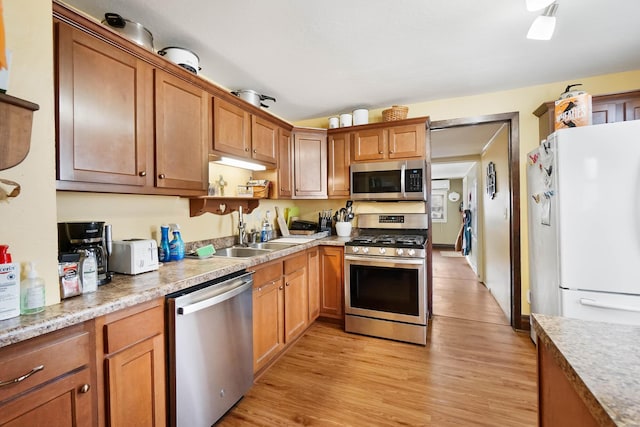 kitchen featuring stainless steel appliances, sink, and light hardwood / wood-style flooring