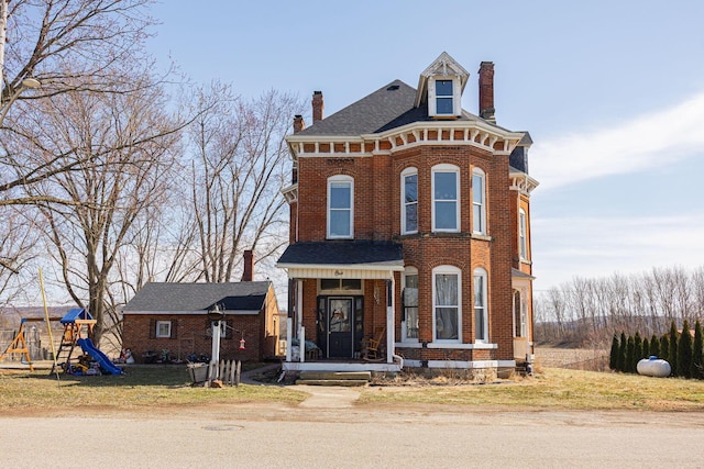 italianate-style house with brick siding, a chimney, and a playground