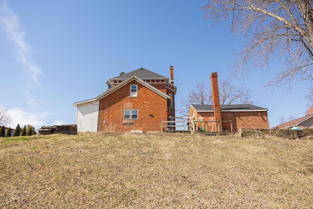 rear view of property featuring brick siding and fence