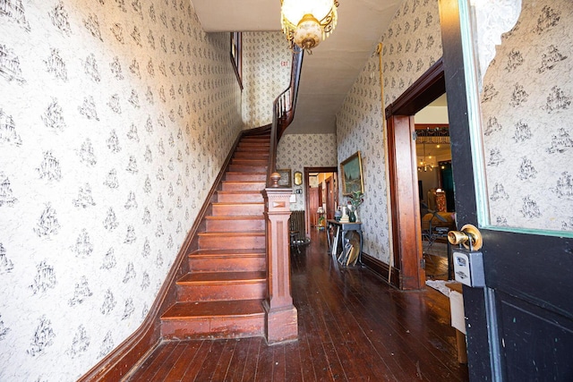 stairway featuring wallpapered walls, baseboards, hardwood / wood-style floors, and a wainscoted wall