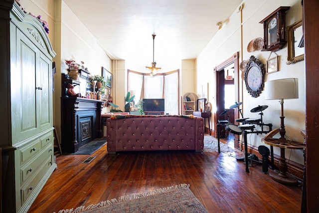 living room featuring dark wood-type flooring, a chandelier, visible vents, and a fireplace with raised hearth