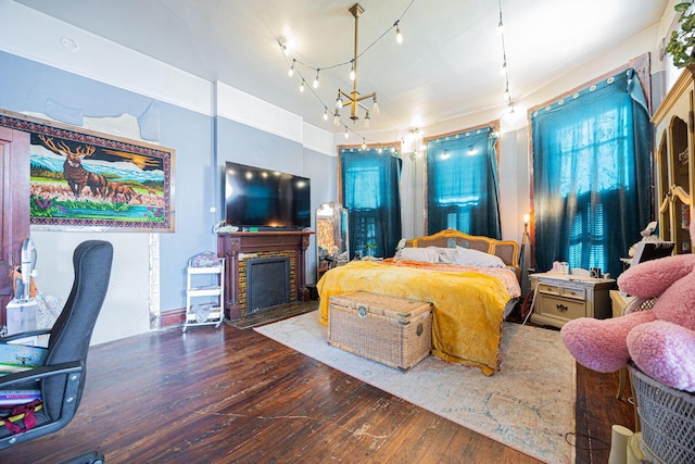 bedroom featuring wood-type flooring, a fireplace with flush hearth, and a notable chandelier