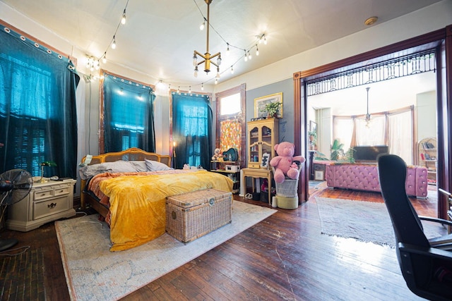 bedroom with hardwood / wood-style flooring, multiple windows, and a notable chandelier