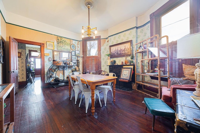 dining space with an inviting chandelier, baseboards, hardwood / wood-style floors, and wallpapered walls