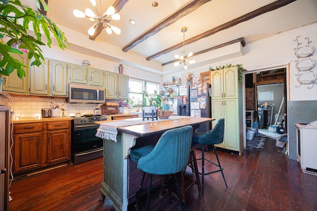 kitchen with beam ceiling, dark wood finished floors, a notable chandelier, stainless steel appliances, and light countertops