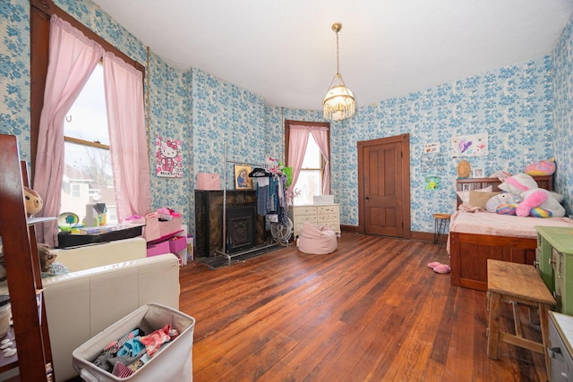 bedroom featuring baseboards, a fireplace, hardwood / wood-style flooring, and wallpapered walls