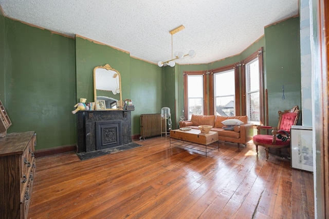 sitting room with a fireplace with flush hearth, baseboards, radiator heating unit, and hardwood / wood-style flooring