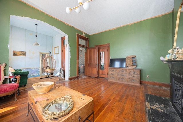 living room with baseboards, a textured ceiling, arched walkways, and hardwood / wood-style floors