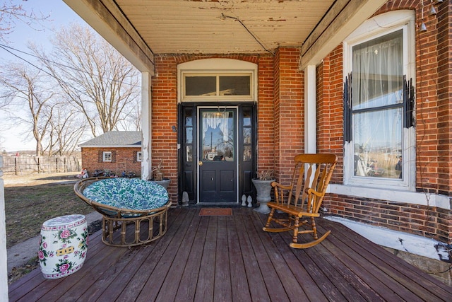 view of exterior entry featuring covered porch and brick siding