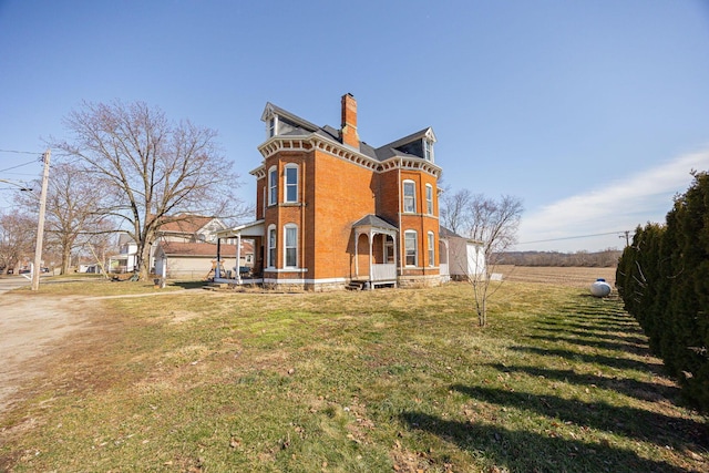 rear view of house featuring a yard, brick siding, and a chimney