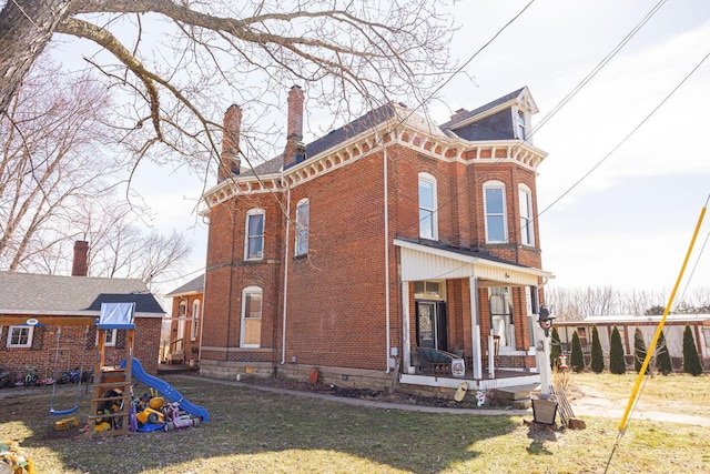 view of front of home featuring covered porch, brick siding, a playground, and a front yard