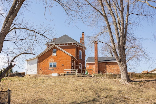 back of house with brick siding and a chimney