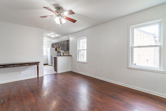 unfurnished living room featuring ceiling fan, hardwood / wood-style floors, and a wealth of natural light