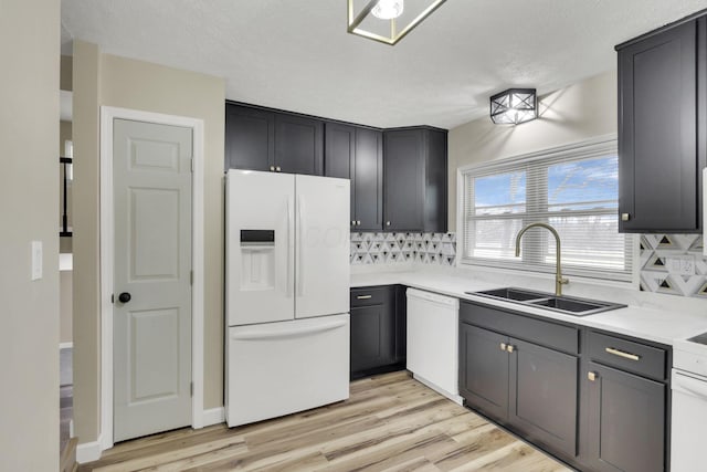 kitchen featuring sink, decorative backsplash, white appliances, and light hardwood / wood-style flooring