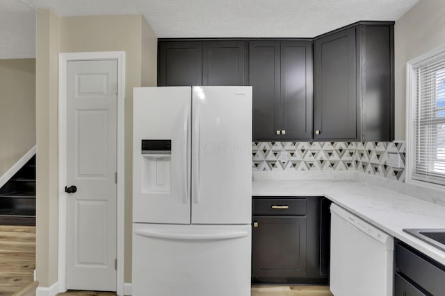 kitchen featuring backsplash, white appliances, and a textured ceiling