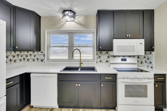 kitchen featuring tasteful backsplash, sink, white appliances, and a textured ceiling