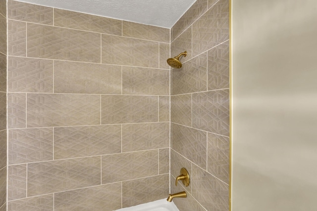 bathroom featuring tiled shower / bath and a textured ceiling