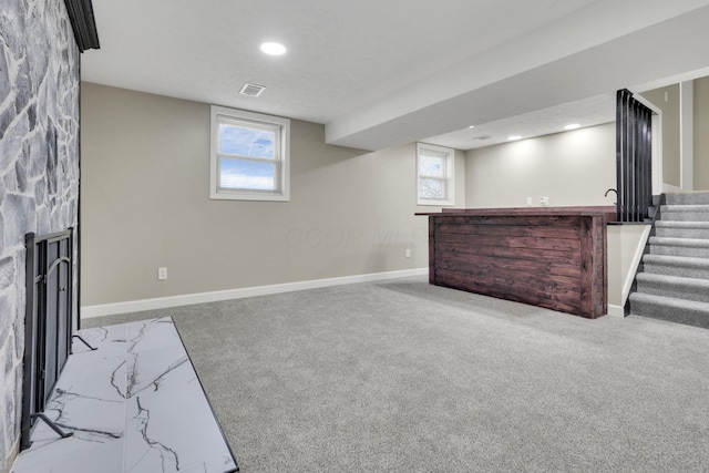 basement featuring light colored carpet and a fireplace