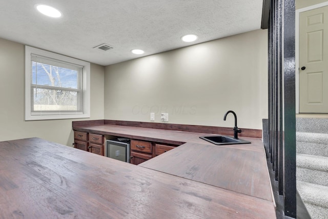 kitchen with sink, beverage cooler, and a textured ceiling