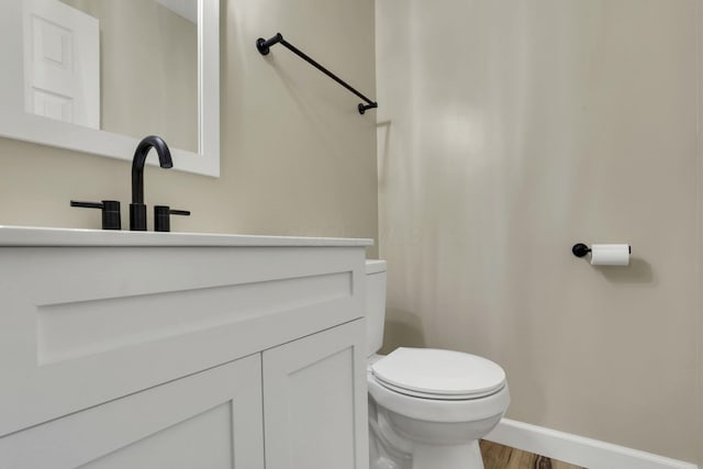 bathroom with wood-type flooring, toilet, and vanity