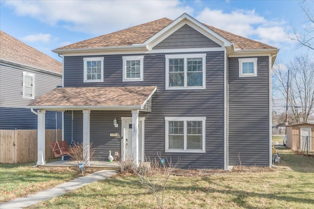 view of front of house with covered porch, roof with shingles, fence, and a front yard