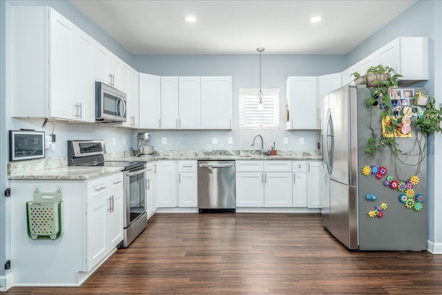 kitchen with light stone countertops, white cabinetry, appliances with stainless steel finishes, and a sink