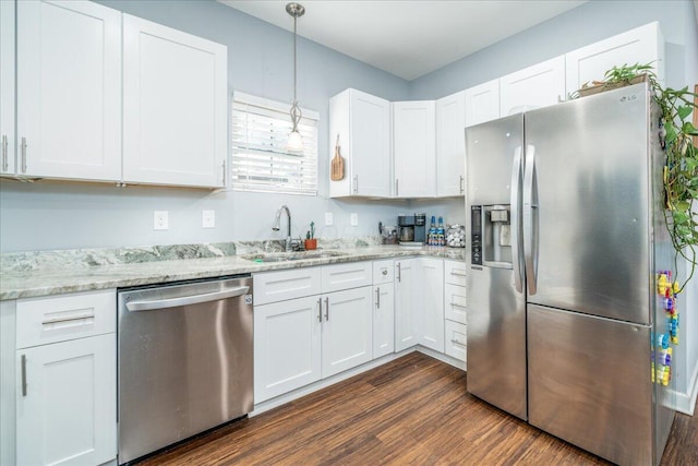 kitchen featuring dark wood finished floors, stainless steel appliances, hanging light fixtures, white cabinets, and a sink