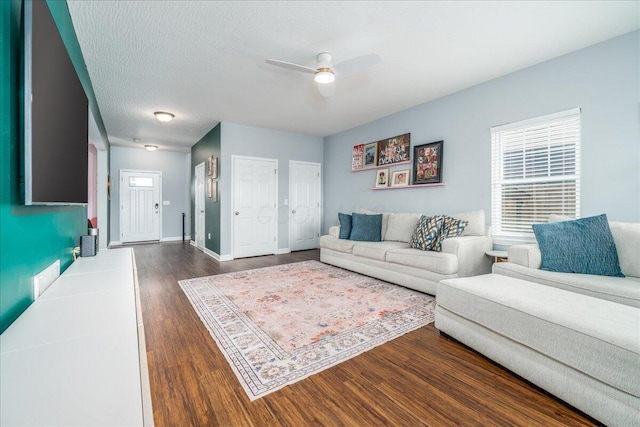 living room featuring ceiling fan, dark hardwood / wood-style flooring, and a textured ceiling