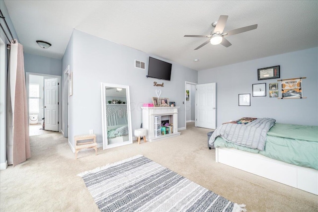 bedroom with light carpet, baseboards, visible vents, and a fireplace with raised hearth