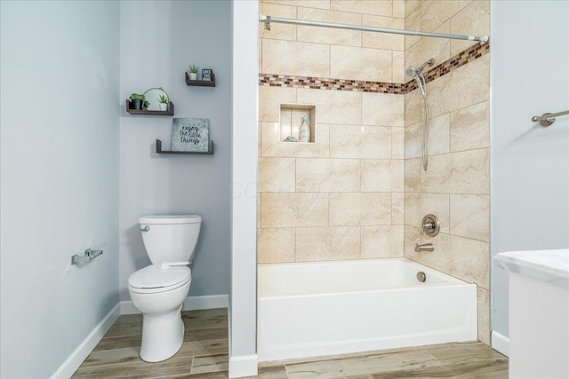 bathroom with baseboards, tub / shower combination, toilet, and wood finished floors