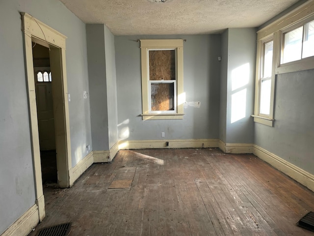 empty room with dark wood-type flooring and a textured ceiling