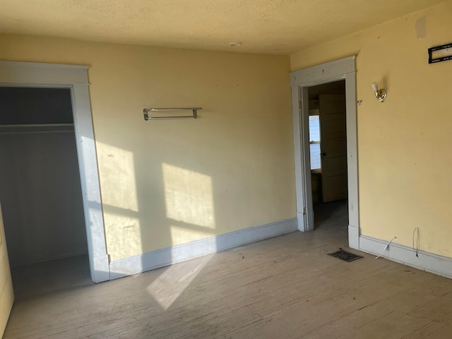 unfurnished room with light hardwood / wood-style flooring and a textured ceiling