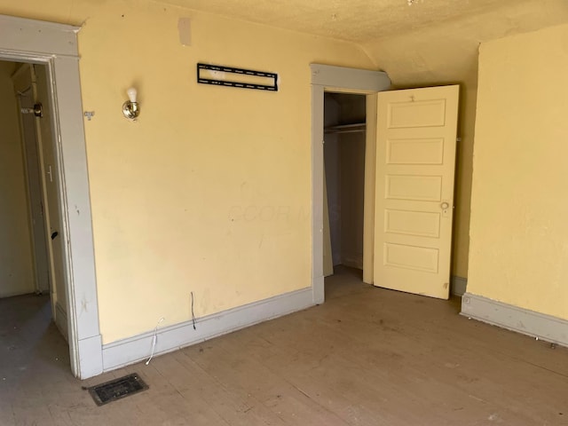 unfurnished bedroom featuring lofted ceiling, hardwood / wood-style flooring, and a closet