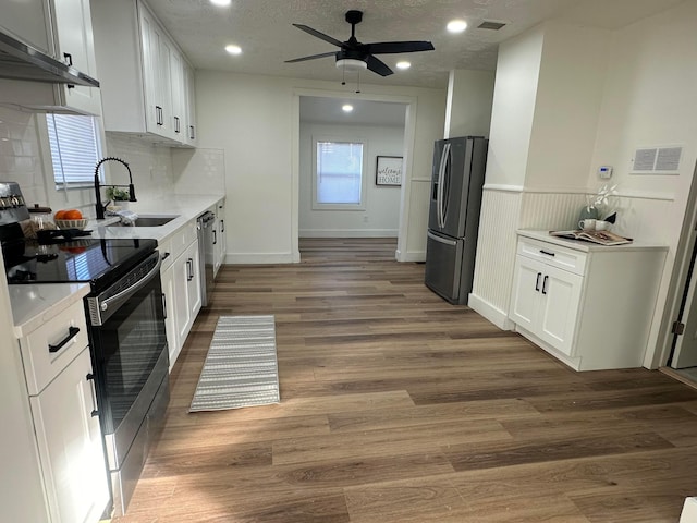 kitchen with stainless steel appliances, sink, white cabinets, and dark hardwood / wood-style flooring