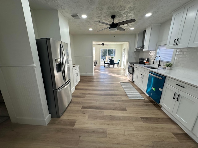 kitchen featuring sink, appliances with stainless steel finishes, white cabinetry, light hardwood / wood-style floors, and decorative backsplash