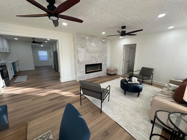 living room featuring wood-type flooring, a textured ceiling, and a fireplace