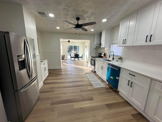 kitchen featuring sink, stainless steel appliances, light hardwood / wood-style floors, and white cabinets